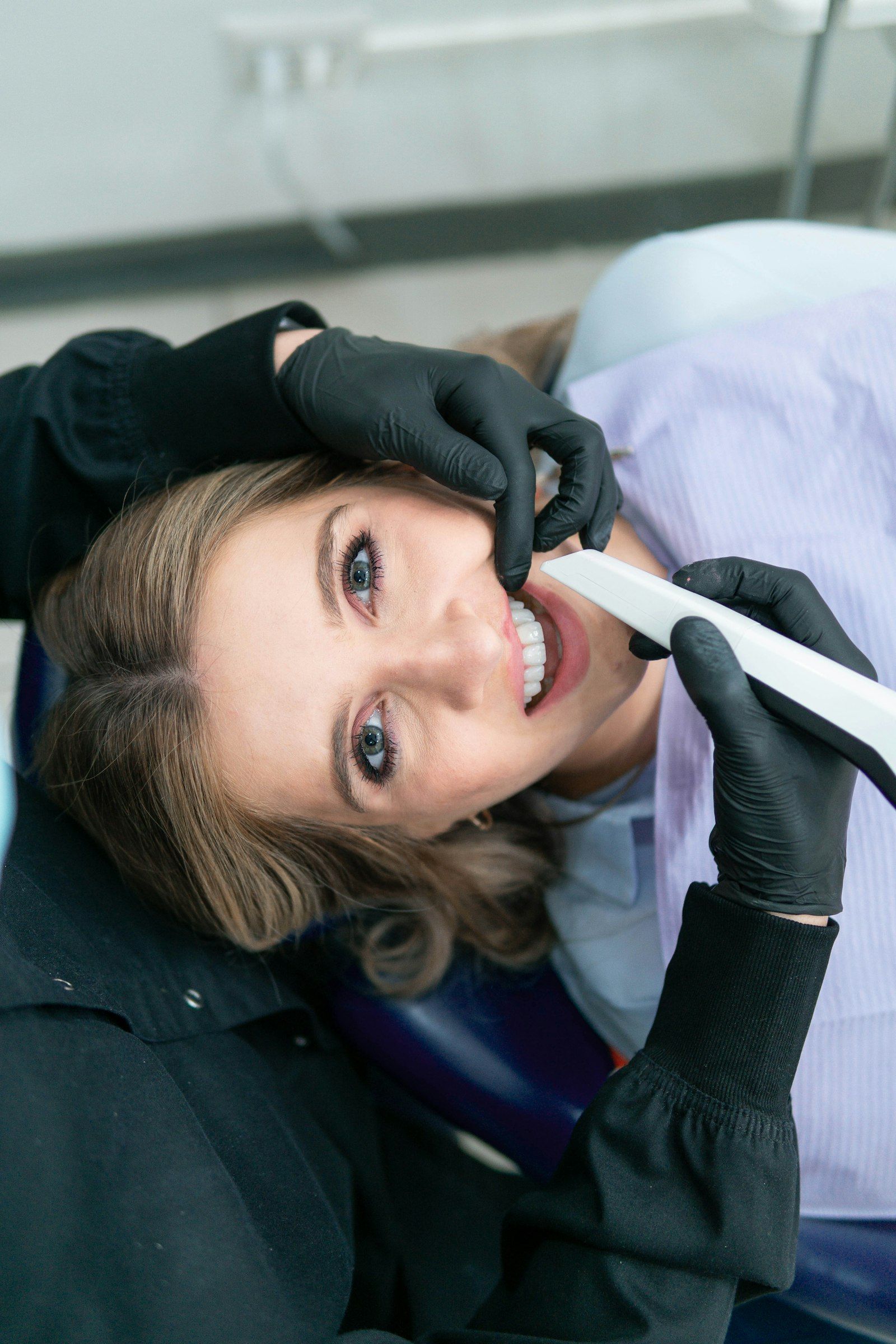 Zahnärztin scannt die Zähne einer Patientin mit einem Intraoralscanner